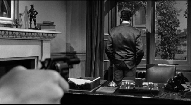 Believing Margaret Abbott (Judith Stott)'s accusation, Fred Jennings (Bill Mitchell) threatens Norman Taylor (Peter Wyngarde) with a gun in Sidney Hayers' Night of the Eagle (1962)