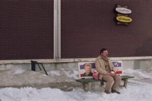 Matthew (director Matthew Rankin) waits for his rendezvous with Massoud outside Tim Horton's in Universal Language (2024)